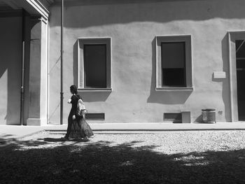 Side view of woman standing by window of building