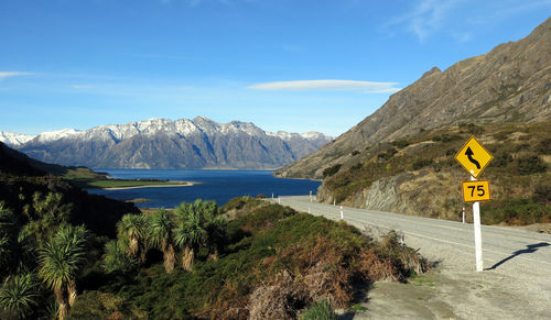 Empty road by mountain leading towards lake