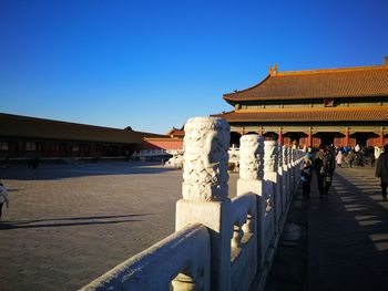 Group of people outside building against clear blue sky