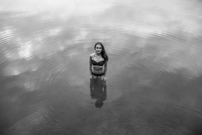 High angle portrait of young woman wearing bikini standing in lake