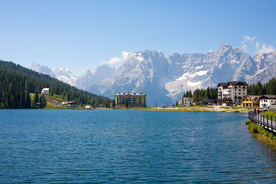 Scenic view of lake by buildings against sky during winter