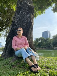 Woman sitting on tree trunk in park