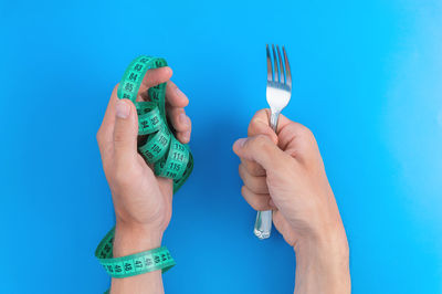 Cropped hand of woman holding ice cream against blue background