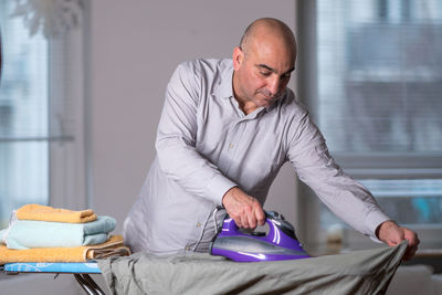 Man ironing clothes at home