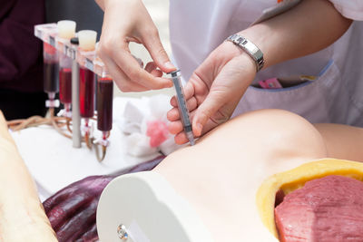 Midsection of doctor injecting mannequin