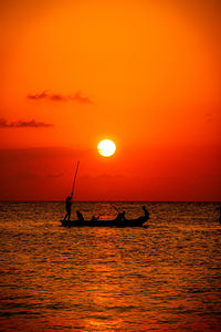 Silhouette boat in sea against orange sky