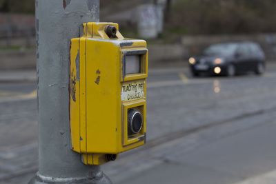 Close-up of yellow signal button on street