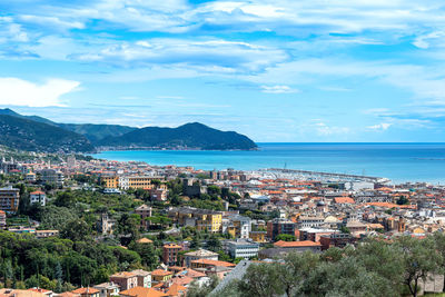 Aerial view of townscape by sea against sky