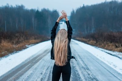 Rear view of woman standing on snow covered road