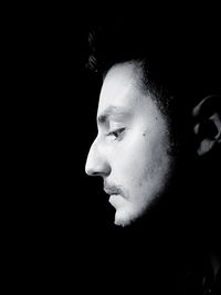 Close-up portrait of young man against black background