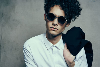 Portrait of young man wearing sunglasses against wall