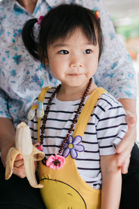 Midsection of parent with daughter holding banana