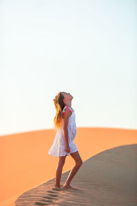 Full length of woman standing against clear sky during sunset