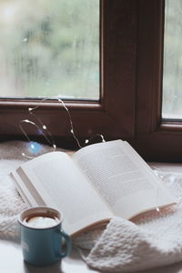 Close-up of open book on window sill at home