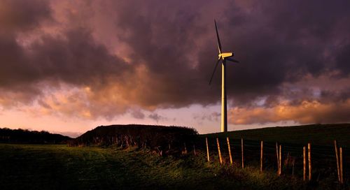 Windmill on field against cloudy sky
