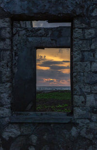 Window of old building against sky at sunset