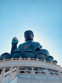 Low angle view of giant buddha statue against clear blue sky