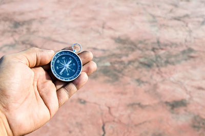 Cropped hand of person holding navigational compass at park