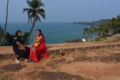 People sitting by sea against sky