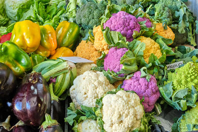 Differrent kinds of colorful caulifower and other vegetables for sale at a market