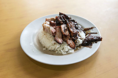 High angle view of rice with roasted pork in plate on table