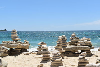 Stack of stones by sea against clear blue sky