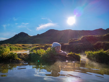 Woman relaxing at hot spring against mountain