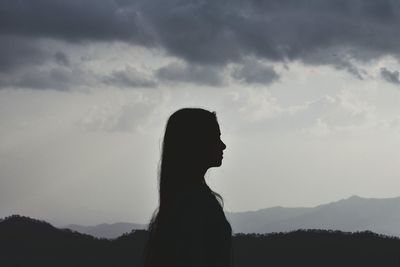 Silhouette woman standing by mountain against sky