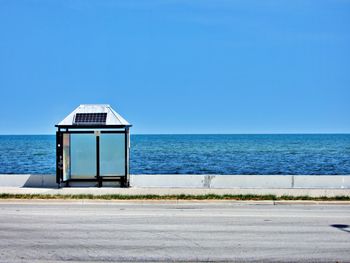 Lifeguard hut on sea against clear blue sky