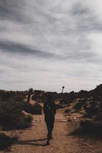 Silhouette of man standing on sand against sky