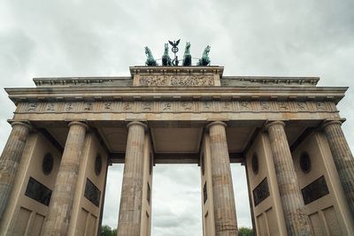 Low angle view of brandenburg gate against cloudy sky