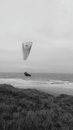 Powered hang glider over beach against sky