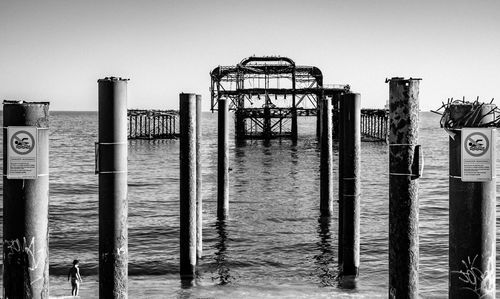 Wooden post on pier by sea against clear sky