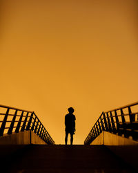 Silhouette man standing on staircase against sky during sunset