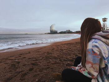 Rear view of woman sitting on beach