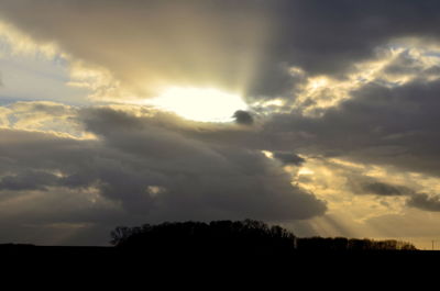 Low angle view of silhouette trees against dramatic sky