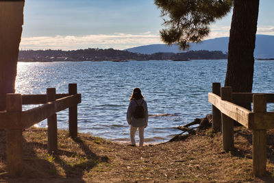 Girl standing at the end of a path and staring at the sea