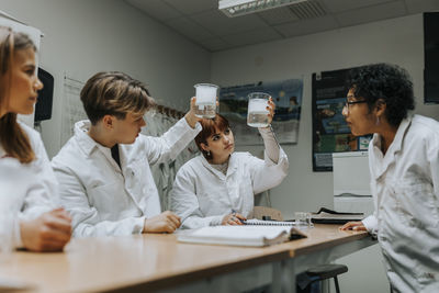 Teacher and students examining chemical in beaker at school laboratory