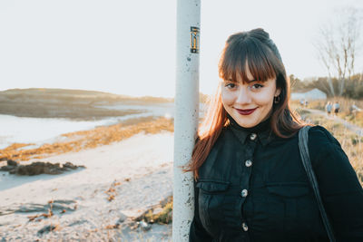 Portrait of young woman standing by lake