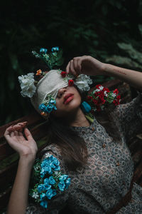 Portrait of young woman holding flowers at garden