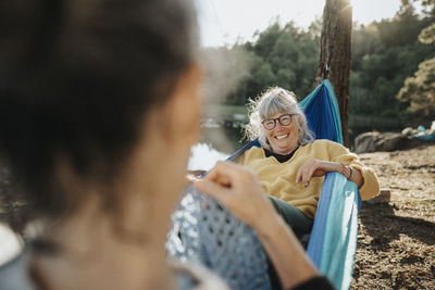 Two senior women resting in hammock at lakeshore