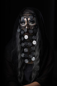 Portrait of woman wearing mask against black background