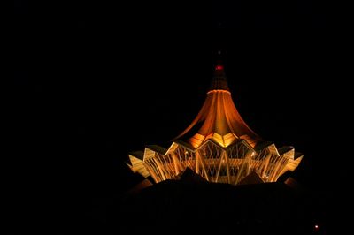 Low angle view of illuminated lighting equipment against black background