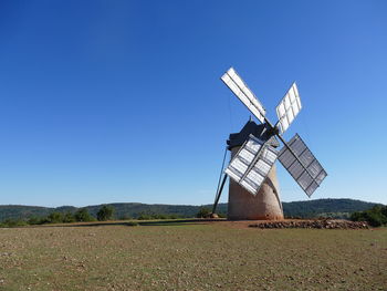 Traditional windmill on field against clear sky