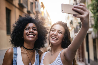 Smiling friends talking selfie in city