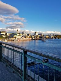 Buildings by river against sky in city