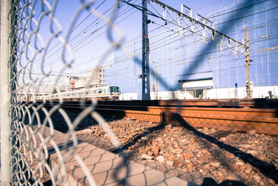 View of railroad tracks through metal fence 