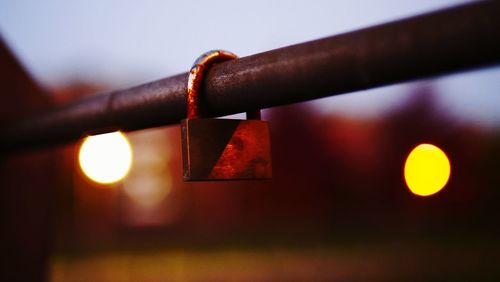 Close-up of padlocks hanging on railing against sky at night