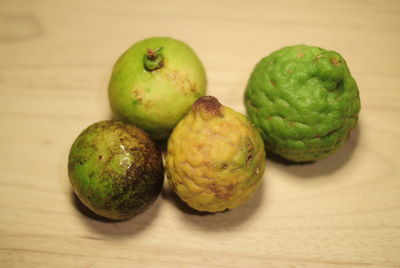 Close-up of kaffir limes and lemon on wooden table