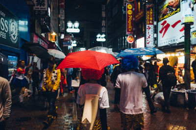 Rear view of people walking on wet street at night